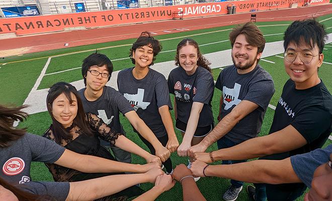 International students with hands inside a circle